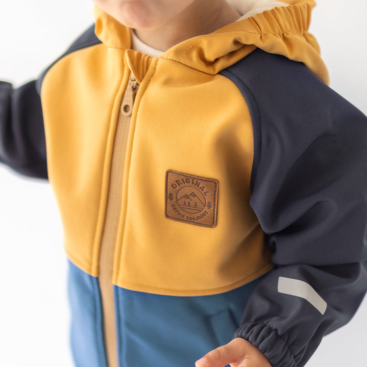 Photo d'un enfant portant le manteau bleu et jaune en coquille souple, bébé