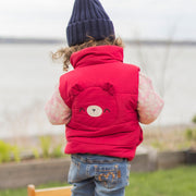 Photo d'un bébé de dos portant la veste doudoune sans manches rouge framboise, bébé