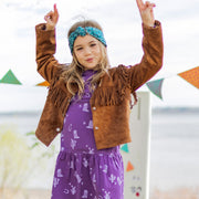 Fille souriante en gros plan portant une veste à franges brune en suède et une robe mauve à motifs western
