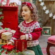 Fillette émerveillée découvrant un cadeau de Noël, vêtue d’un chandail rouge et blanc en tricot festif, collection Souris Mini.